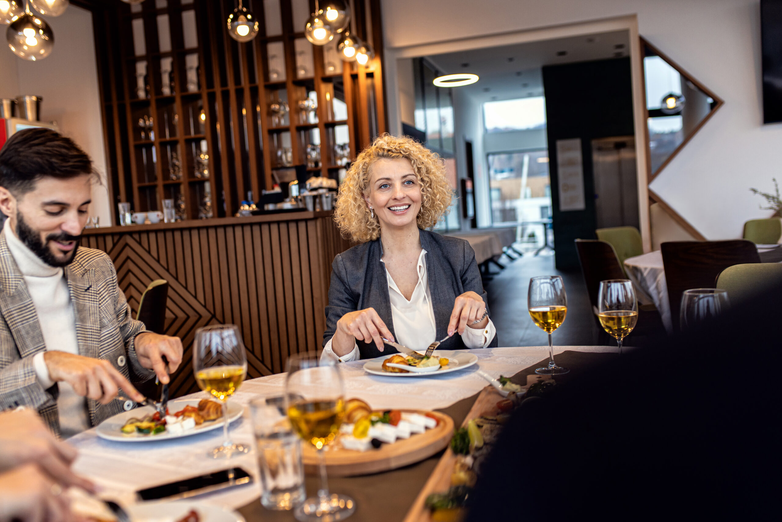 NAŠI RESURSI portrait of businesswoman sitting with coworkers in restaurant,